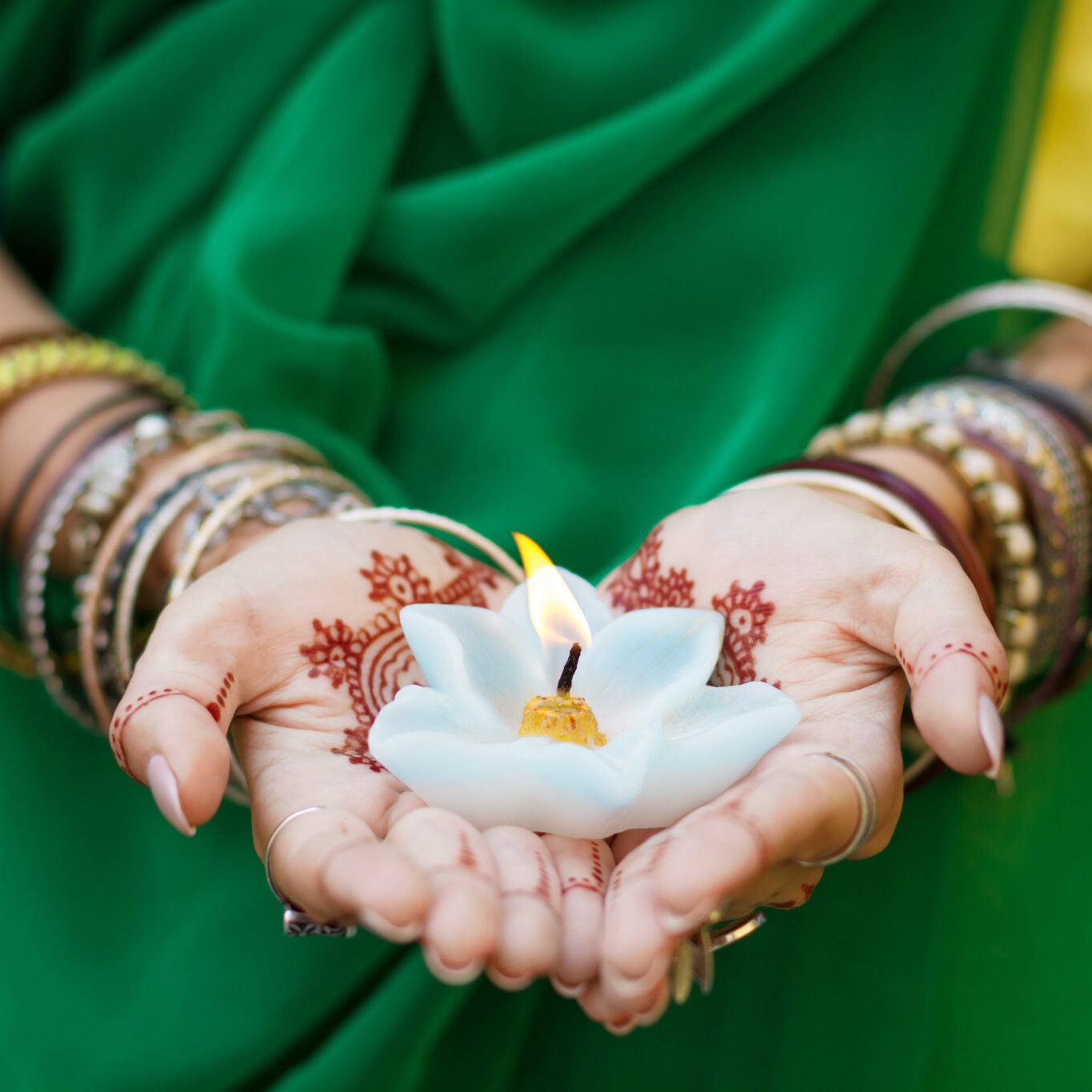 Beautiful woman in traditional Muslim Indian wedding green sari Beautiful woman in traditional Muslim Indian wedding green sari dress hands with henna tattoo mehndi pattern jewelry and bracelets hold burning lotus candle Summer culture festival celebration concept